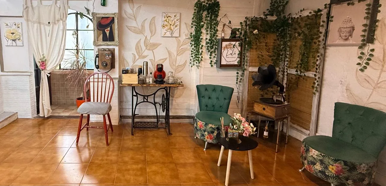 Sala de espera de Lalá Hair & Style, con mural de hojas pintado a mano y sillones verdes